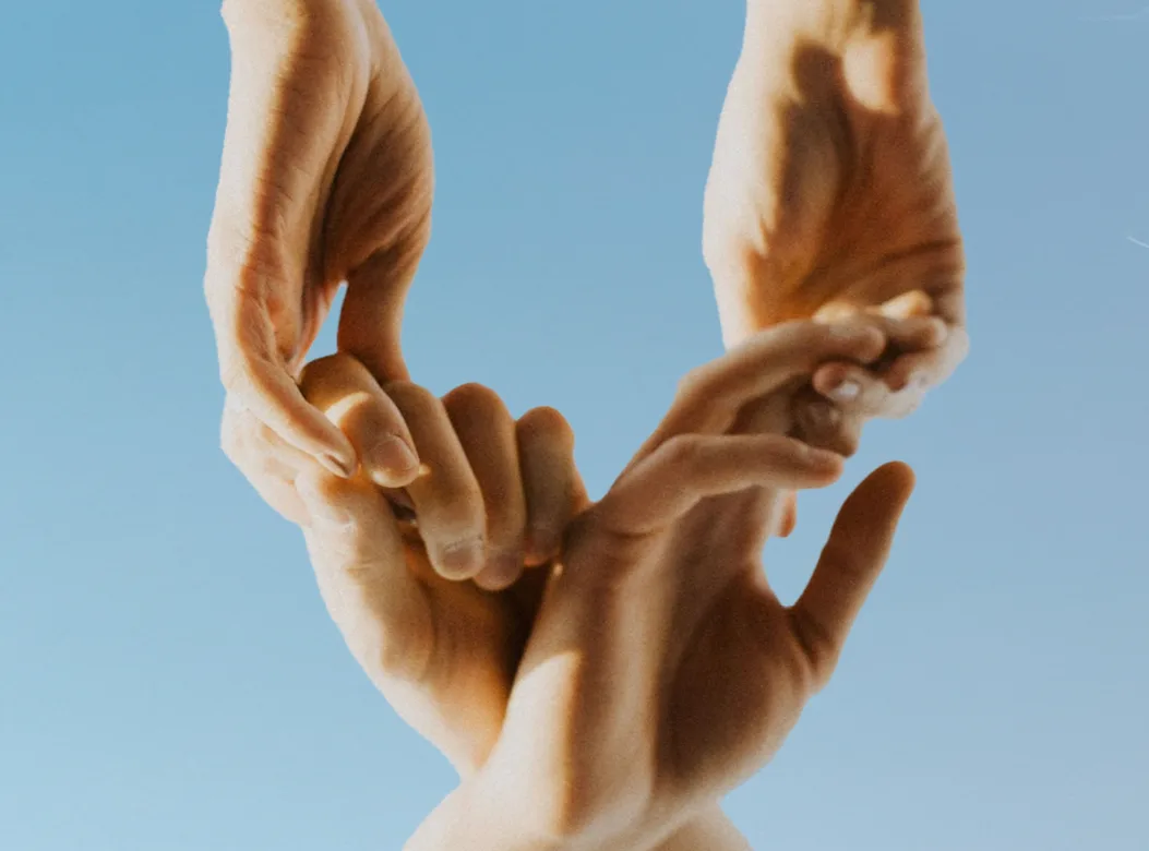 Human hands forming a heart against a blue background.